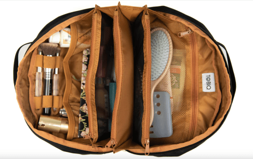 A top view of a cosmetic bag with organized compartments containing beauty products and a hairbrush.